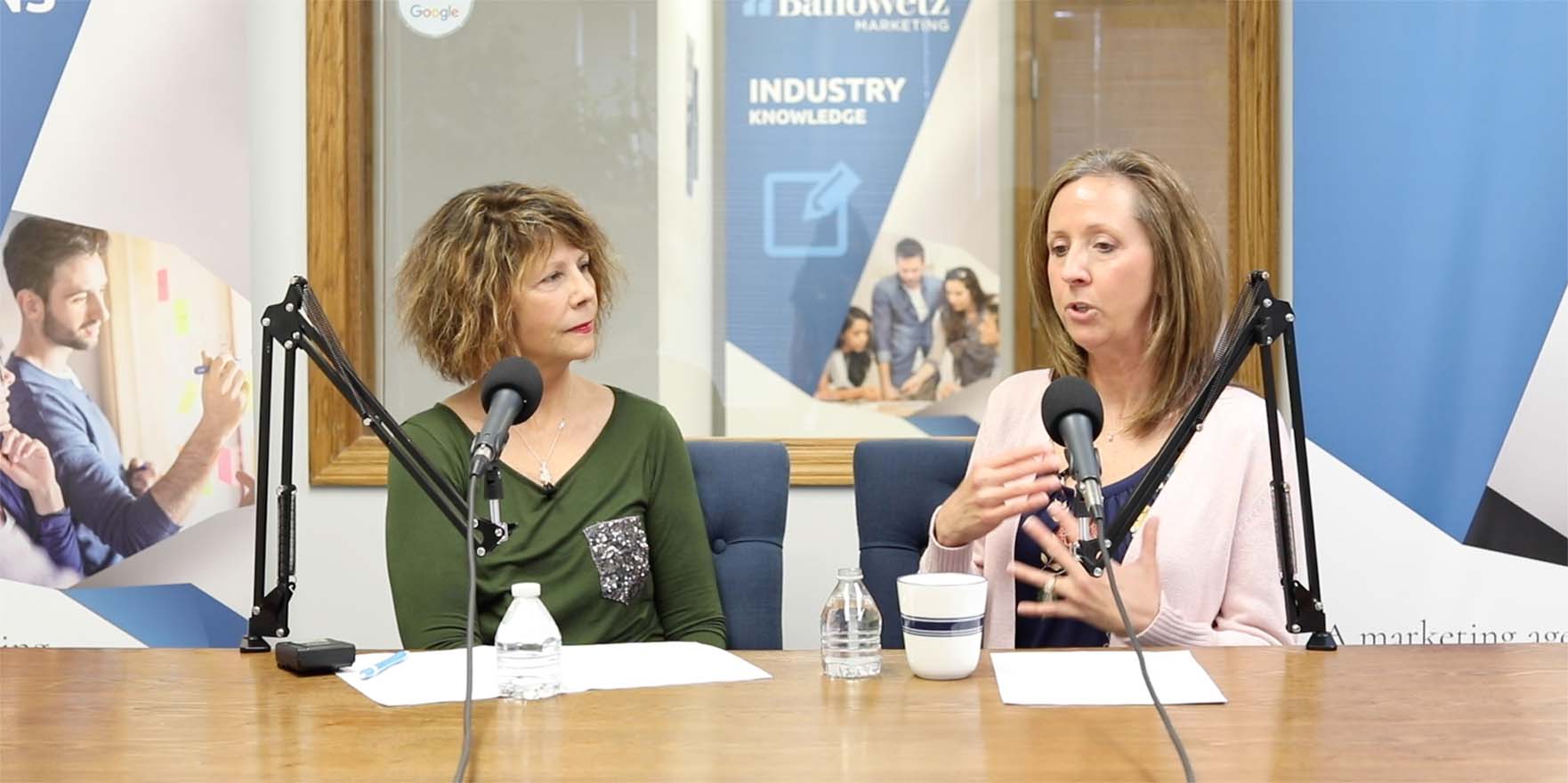 Stephanie and June talk to each other in front of microphones while recording a Banowetz Marketing podcast in Cedar Rapids, Iowa.