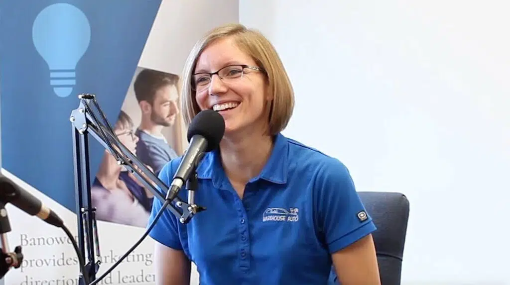 Smiling woman talks into a microphone while recording a podcast.